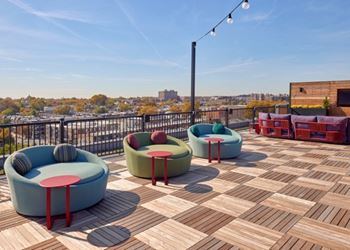 A wooden deck with three round chairs and two small tables.